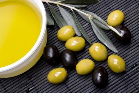 olivový olej v misce a zelené i čierné olivy na proutené podložce