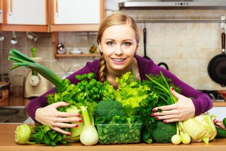 mladá žena má před sebou mnozstvo cerstvé zeleniny